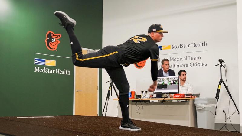 巴尔的摩金莺队运动员抛出一个音高而医生肖恩·科廷看起来在MedStar保健运动医学投手在贝尔实验室空气,马里兰州。