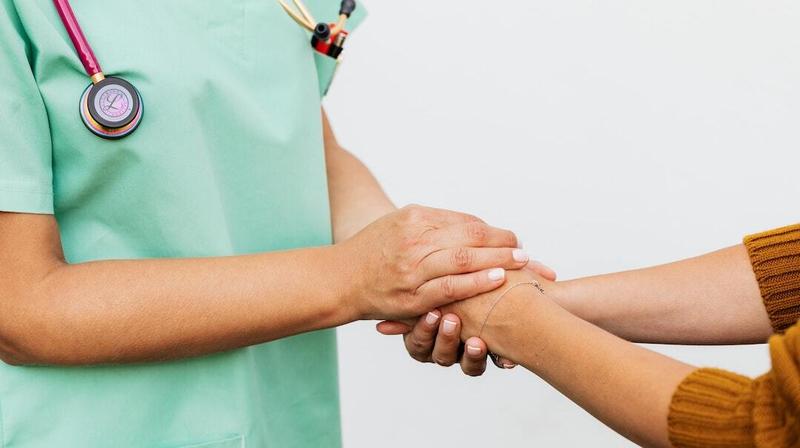 Close up photo of a doctor holding the hands of a patient.
