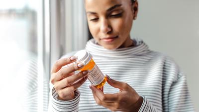 A young woman reads a prescription bottle.