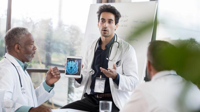 Doctors consult while looking at a scan of the human brain.