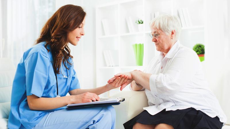 A healthcare worker looks at the skin of a mature female patient.