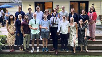 A group of faculty members gathers for a casual group photo outdoors.