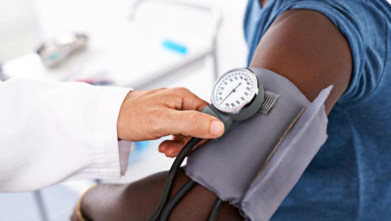 A close up photo of a blood pressure cuff on the arm of an african american male patient. 