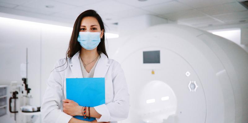 Portrait of a female doctor in the CT scanner room wearing a protective face mask.