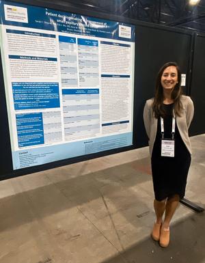 A student in MedStar Health's Otolaryngology Head and Neck Surgery Residency program stands next to her abstract presentation at a conference.