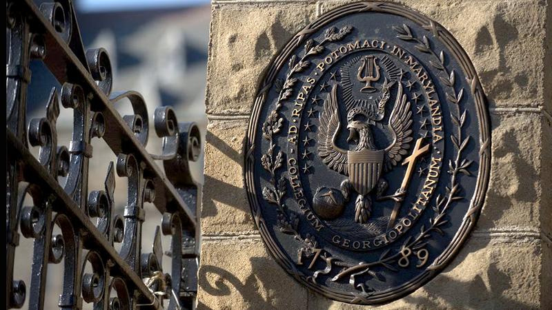 Historic stone and iron entrance gate with the university seal on the campus of Georgetown University, Washington DC