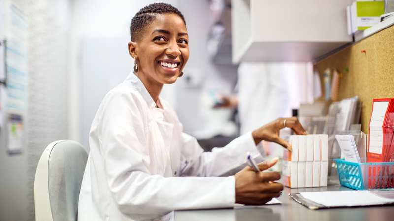 A pharmacist sits at a table in a clinical pharmacy.