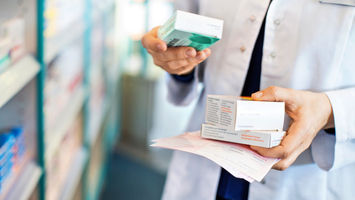 Close up photo of a pharmacist's hands holding prescription boxes.