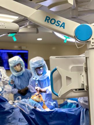 Close up photo of ROSA robotic surgical arm used in knee replacement surgery with surgeons out of focus in the background.