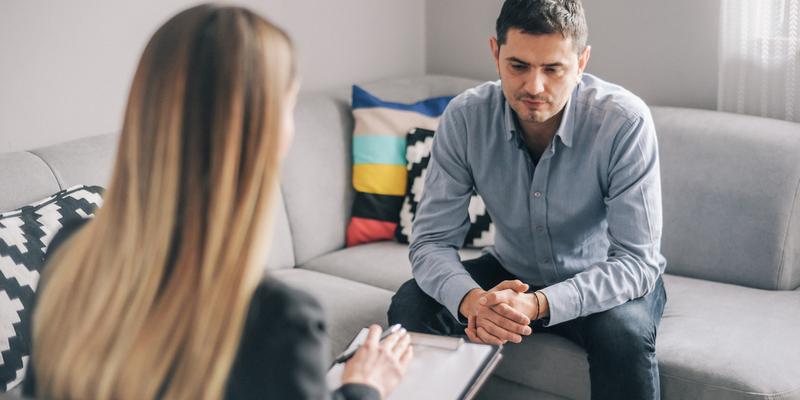 A young man talks with a therapist in an office setting.