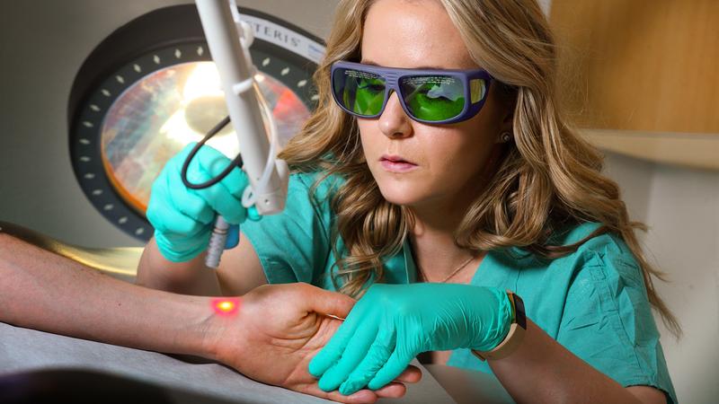 Dr Taryn Travis demonstrates the use of laser therapy equipment on on a patient's arm at MedStar Washington Hospital Center.