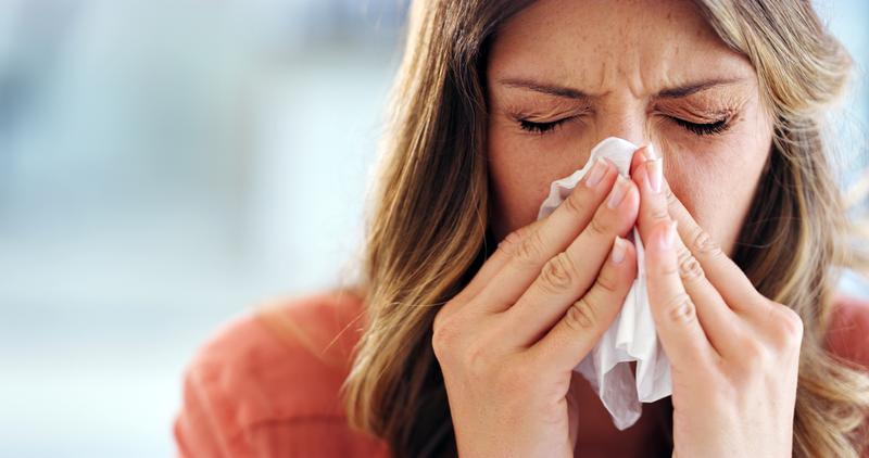 A woman with a cold blows her nose.