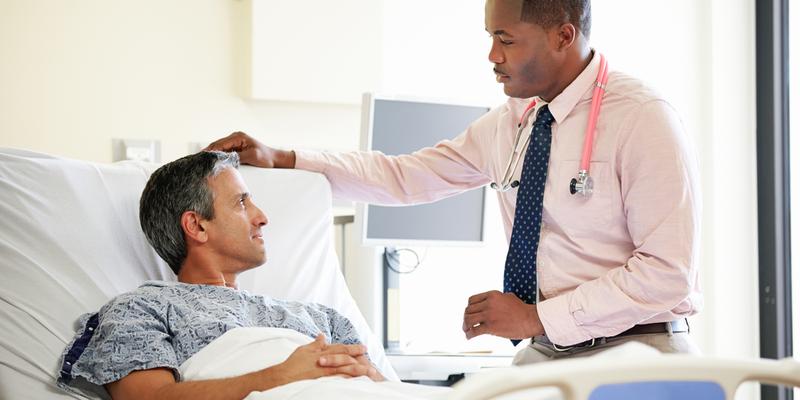 A doctor talks with a patient recovering in a hospital room.