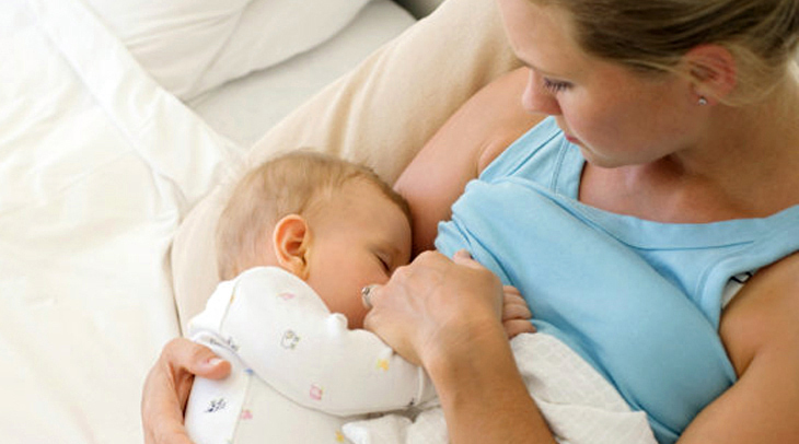 A young woman breastfeeds her newborn baby.
