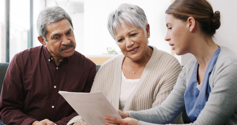 A nurse talks with a husband and wife in a clinical setting.