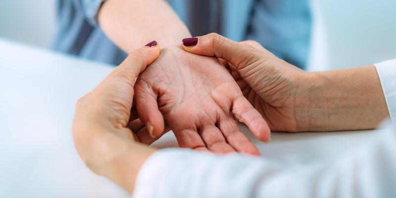 A doctor examines the wrist of a patient experiencing hand pain.