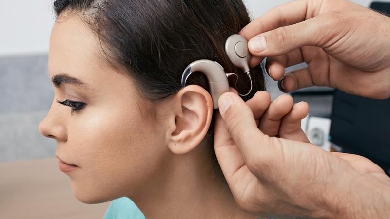 Dr. Selena Briggs poses for a photo while holding a cochlear implant device in her office at MedStar Health.