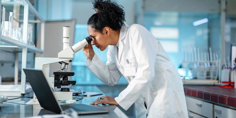 A female scientist looks into a microscope in a laboratory.