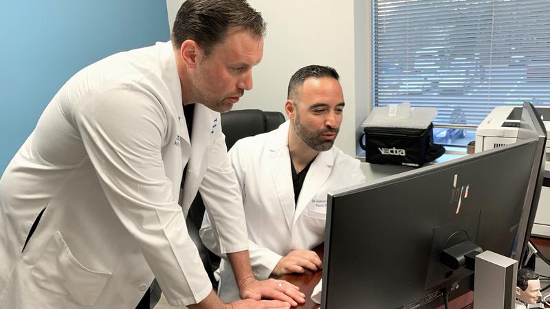 Dr. Andrew Hodge and Dr. Gabriel DelCorral look a computer screen at the MedStar Center for Gender Affirmation.