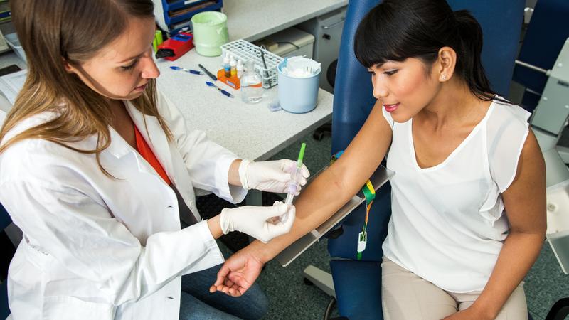 A healthcare professional draws blood from a patient.