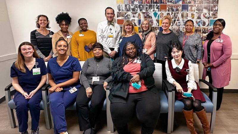 A group of doctors, nurses and staff from the MedStar Health geriatric house calls program pose for a group photo in an office lobby.