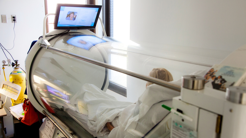 A patient watches television while undergoing treatment in a hyperbaric oxygen therapy chamber.