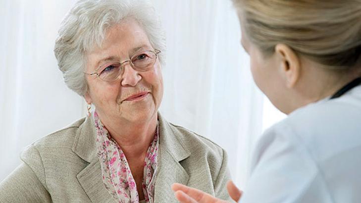 A senior woman talks with her doctor in a clinical setting.