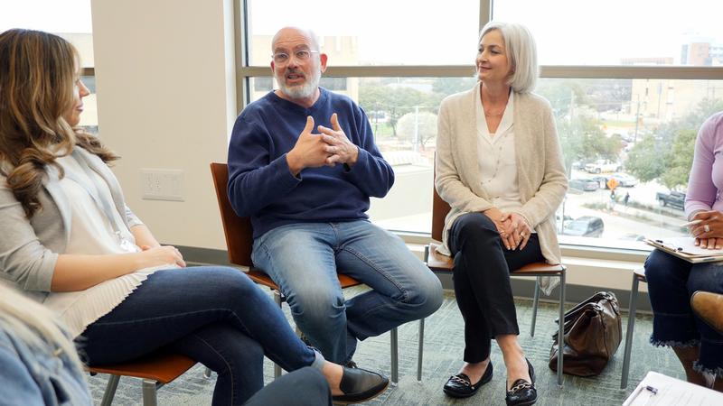 A man sits talks with his support group in a clinical setting.