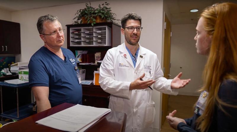 Dr Keith Kowalczyk talks with another medical professional while walking in a clinical office.