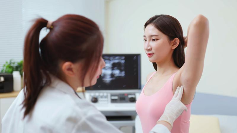 A doctor examines lymph nodes on a female patient in a clinical setting.