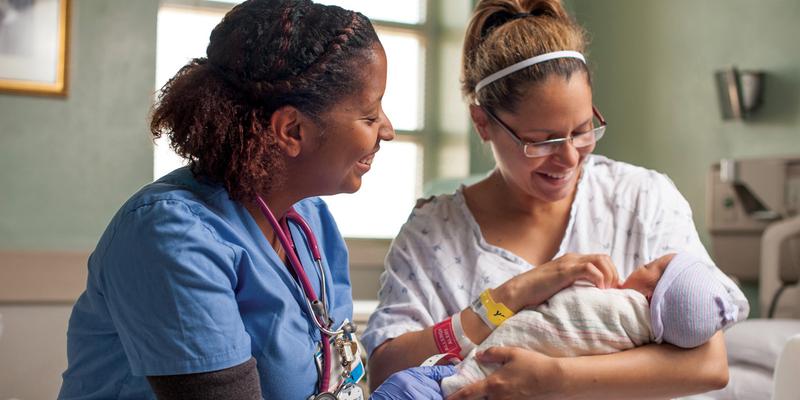 A nurse sits with a mother and her newborn baby at MedStar Health.