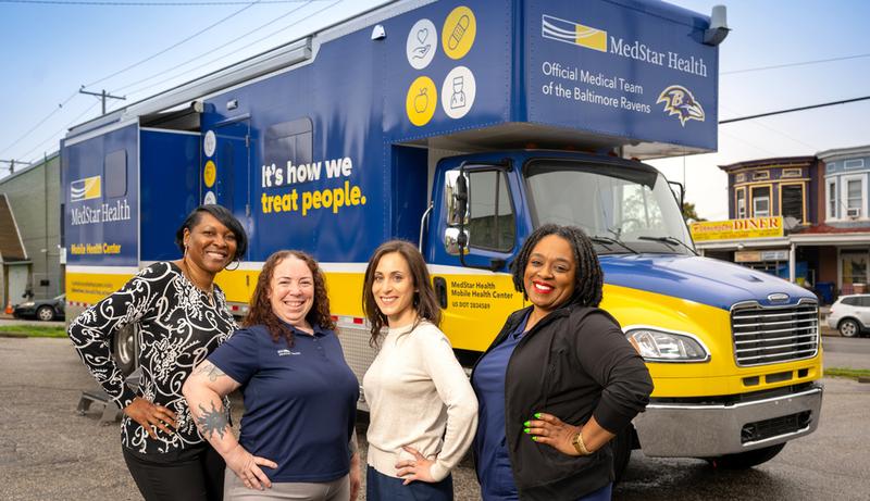 The MedStar Health mobile healthcare team poses for a photo in front of the mobile healthcare center truck.