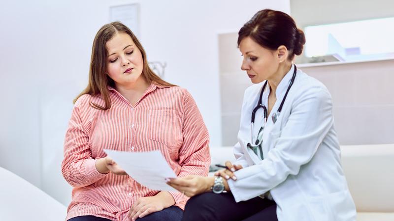 A doctor talks with a patient in a clinical setting.