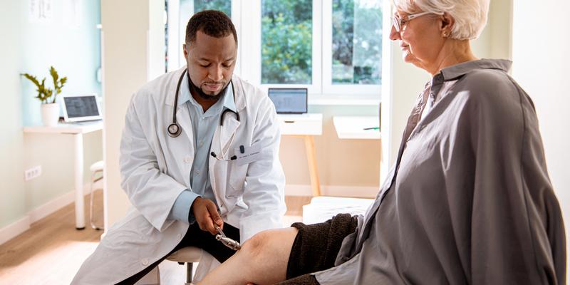 A doctor checks the reflexes of a patient during an office visit.