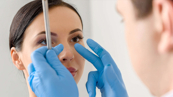 A doctor measures a patient's facial features during an office visit.