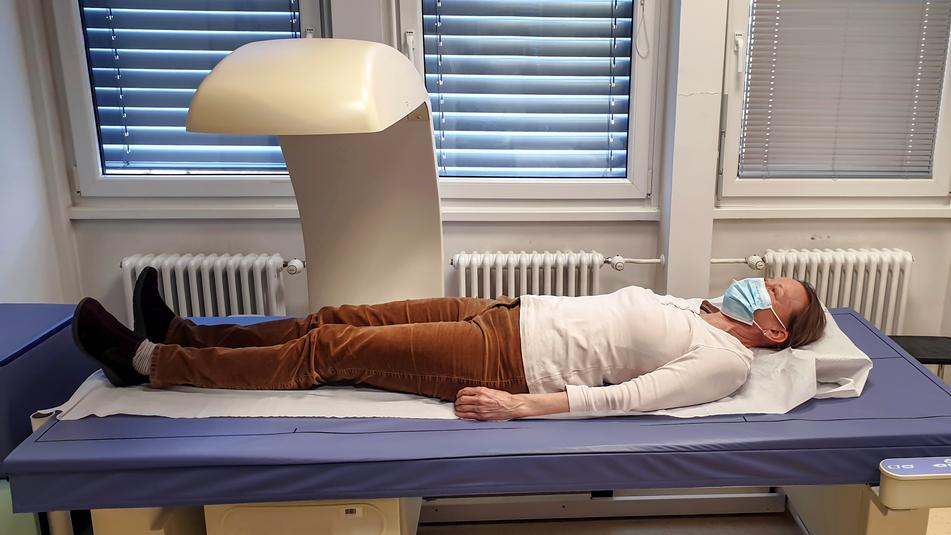 A female patient lays in a bone densitometer scanner while undergoing testing.