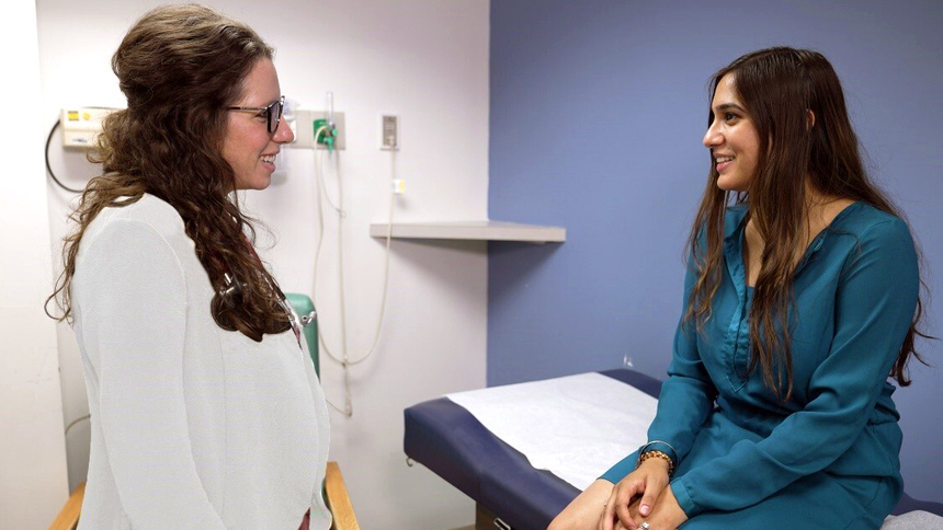 Dr Tara Santum consults with a female patient in a clinical setting.