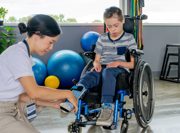 A young boy is fitted with a leg brace at a clininician's office.