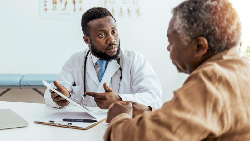 A doctor has a serious conversation with a patient in a clinical setting.