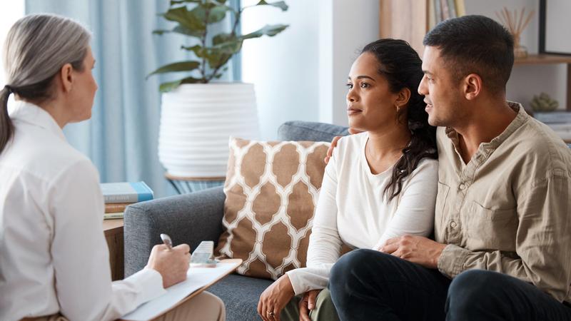 A young couple talks with a counselor in an office setting.