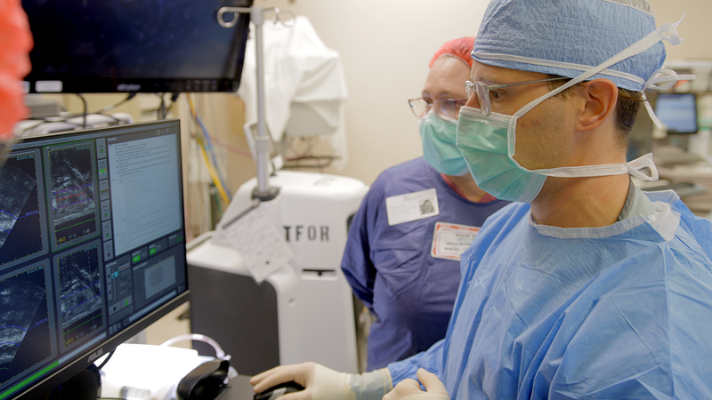 A team of medical professionals performs a medical procedure in an operating room.