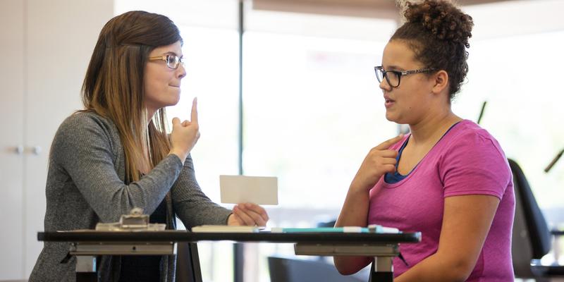 A speech pathologist works with a patient during a therapy session.