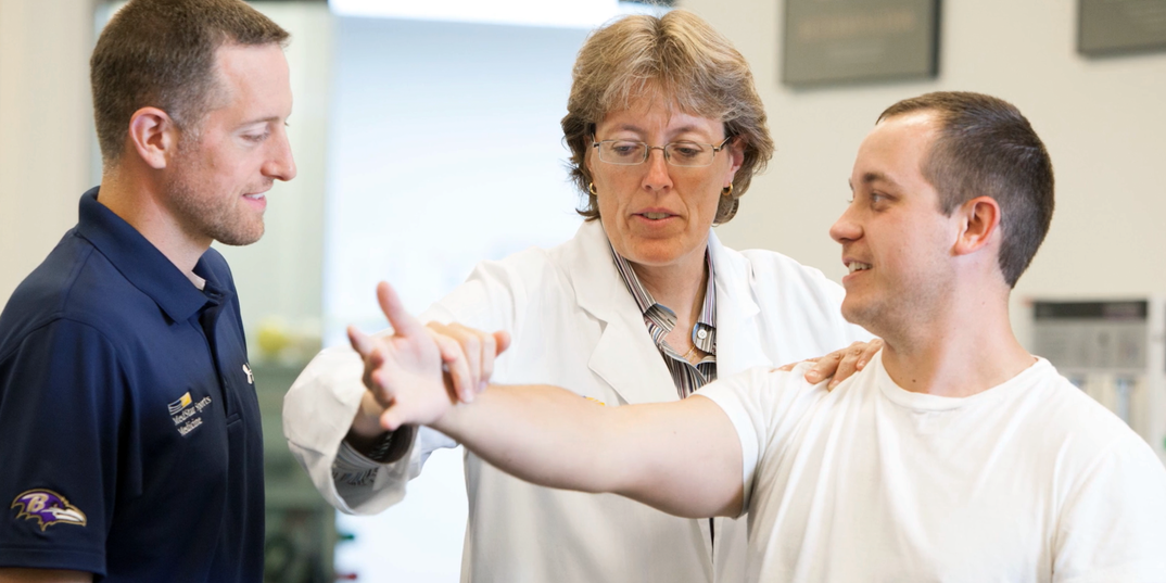 Dr Leigh Ann Curl works with a patient while a fellow MedStar Health sports medicine colleage looks on.