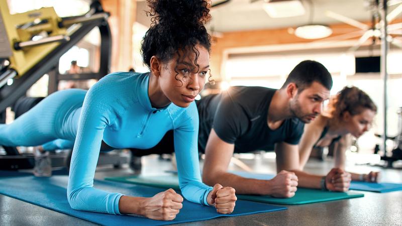 Three people exercise in a gym.