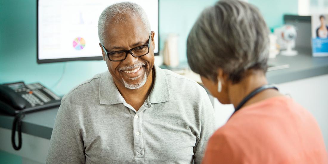 A doctor talks with a senior male african american patient in a clinical setting.