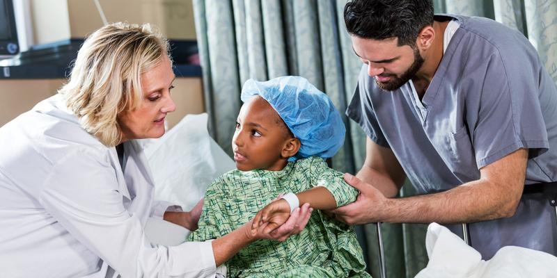 A doctor checks the wrist band of a pediatric surgery patient.