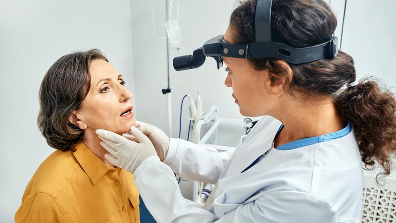 A doctor examines the throat of a female patient.