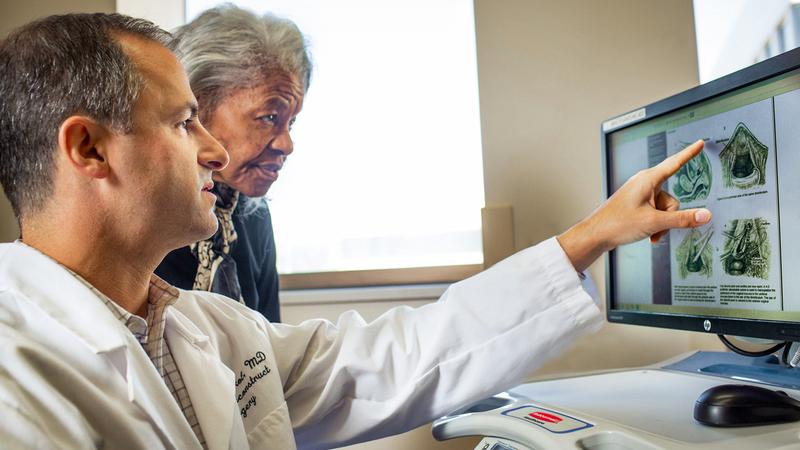 Dr. Andrew Sokol shows imaging scans to a patient in an office setting.