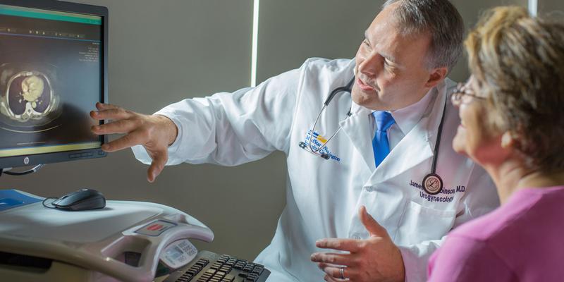 Dr James Robinson consults with a patient, showing the results of a scan on a computer screen.