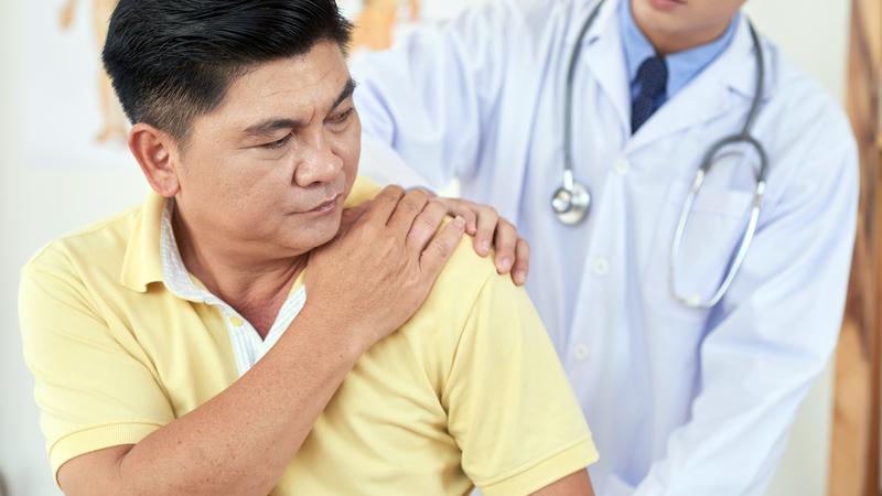 A doctor helps a patient with shoulder pain.